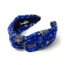 Load image into Gallery viewer, A fabric headband with a knotted center, featuring a blue and gold holiday pattern with menorahs, stars, and stripes, shown on a white background.
