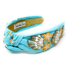 Load image into Gallery viewer, Woman wearing a light blue embellished headband with pearl and floral details paired with star-shaped statement earrings outdoors.