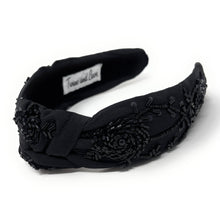 Load image into Gallery viewer, Black floral knot headband embellished with intricate black beadwork, sequins, and embroidered rose details on a soft fabric band.