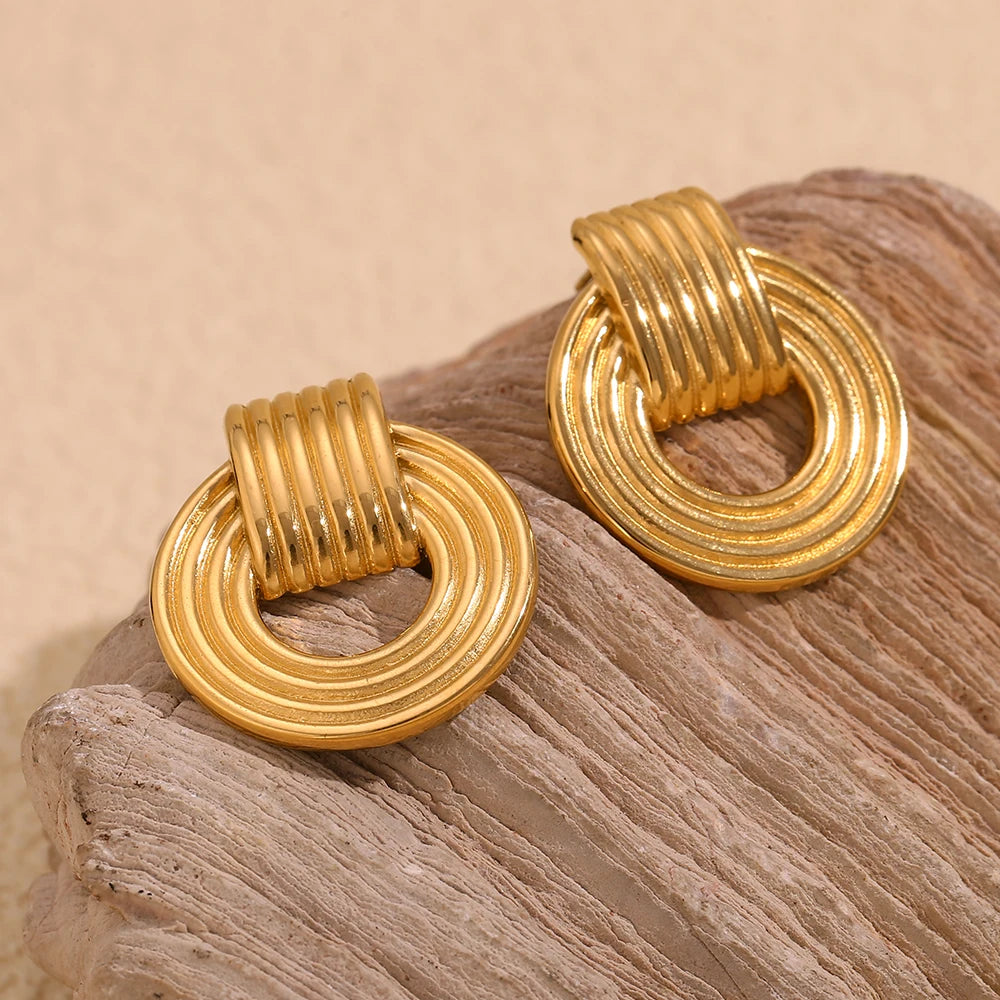18k Gold plated drop earrings on a textured beige surface