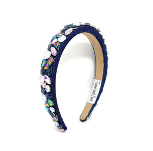 Navy blue headband adorned with colorful, iridescent gemstones, arranged intricately. 