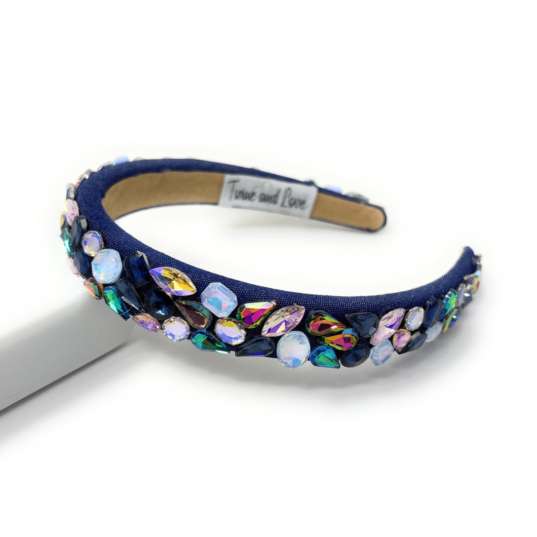 Navy blue headband with colorful gemstones on a white background