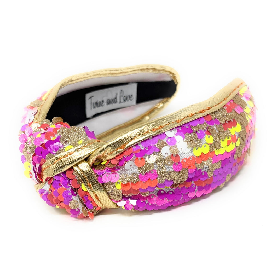 orange, pink and yellow neon sequins headband with a knot design, adorned with multicolored sequins. The vibrant accessory has a playful and chic aesthetic.