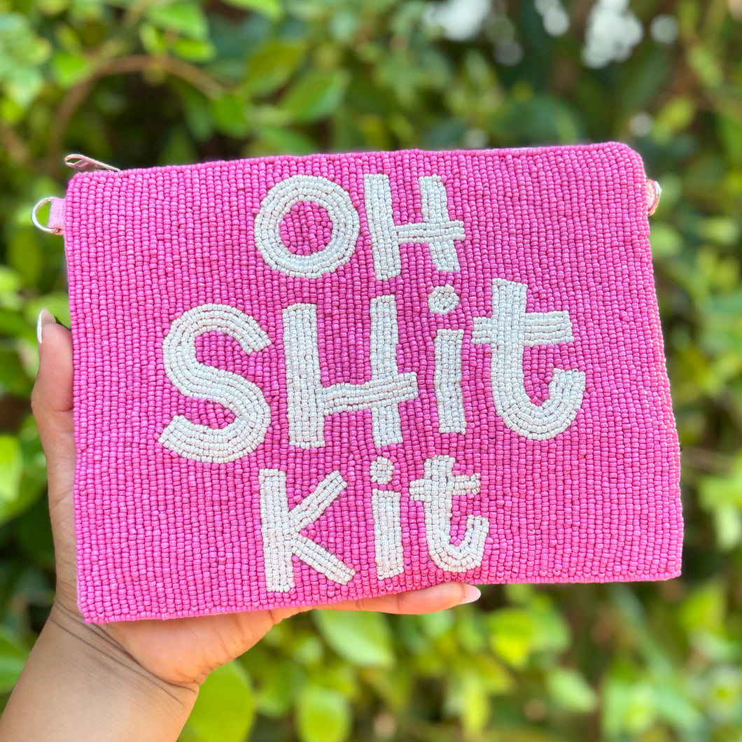 Pink pouch with 'OH SHIT KIT' text held against a green leafy background