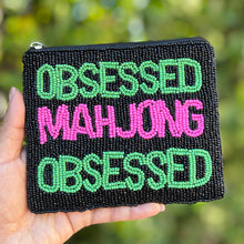 Load image into Gallery viewer, Small pouch with 'Obsessed Mahjong Obsessed' text held in front of a blurred green background