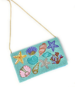 Colorful beaded clutch featuring shells, starfish, and coral on a turquoise background. The vibrant design conveys a lively, ocean-themed vibe.
