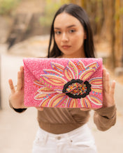 Load image into Gallery viewer, A stylish pink flower clutch bag held by a model in an outdoor setting.