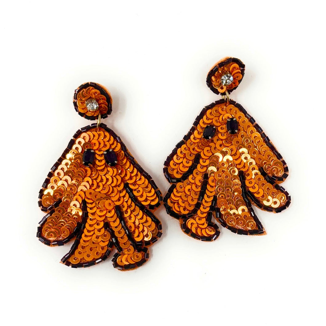 Orange ghost earrings decorated with sequins and black seed beads on a white background. The playful design conveys a fun, festive, and whimsical Halloween theme.