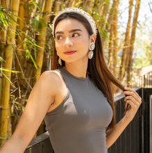 Load image into Gallery viewer, Model styled in a white rhinestone headband and luxe statement earrings against a warm natural backdrop.