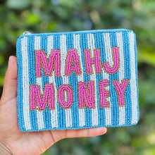 Load image into Gallery viewer, A hand holding a small zippered pouch with blue and white vertical stripes and the words 'MAHJ MONEY' in pink embroidered letters, set against a blurred green outdoor background.