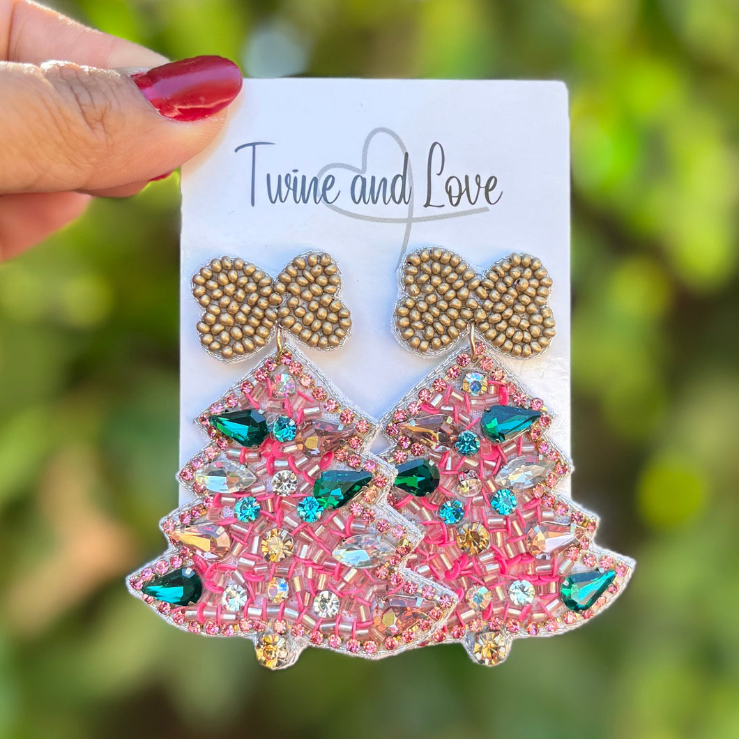 Hand holding a card with decorative earrings against a blurred green background