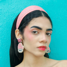 Load image into Gallery viewer, Woman wearing a soft pink padded headband and pink beaded heart-shaped earrings, styled with a black one-shoulder top against a turquoise backdrop.