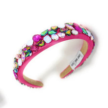 Load image into Gallery viewer, A vibrant pink headband adorned with multicolored gemstones, including blue, purple, and green. It exudes a playful, glamorous vibe.
