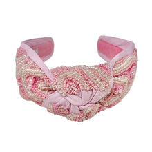 Load image into Gallery viewer, Pink padded headband adorned with intricate beadwork in swirling patterns. It features a central knot, creating an elegant and textured design.