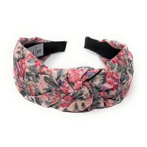 Floral headband with pink, purple, and dark green pattern on a white background. It features a central knot, creating a vibrant, stylish look.