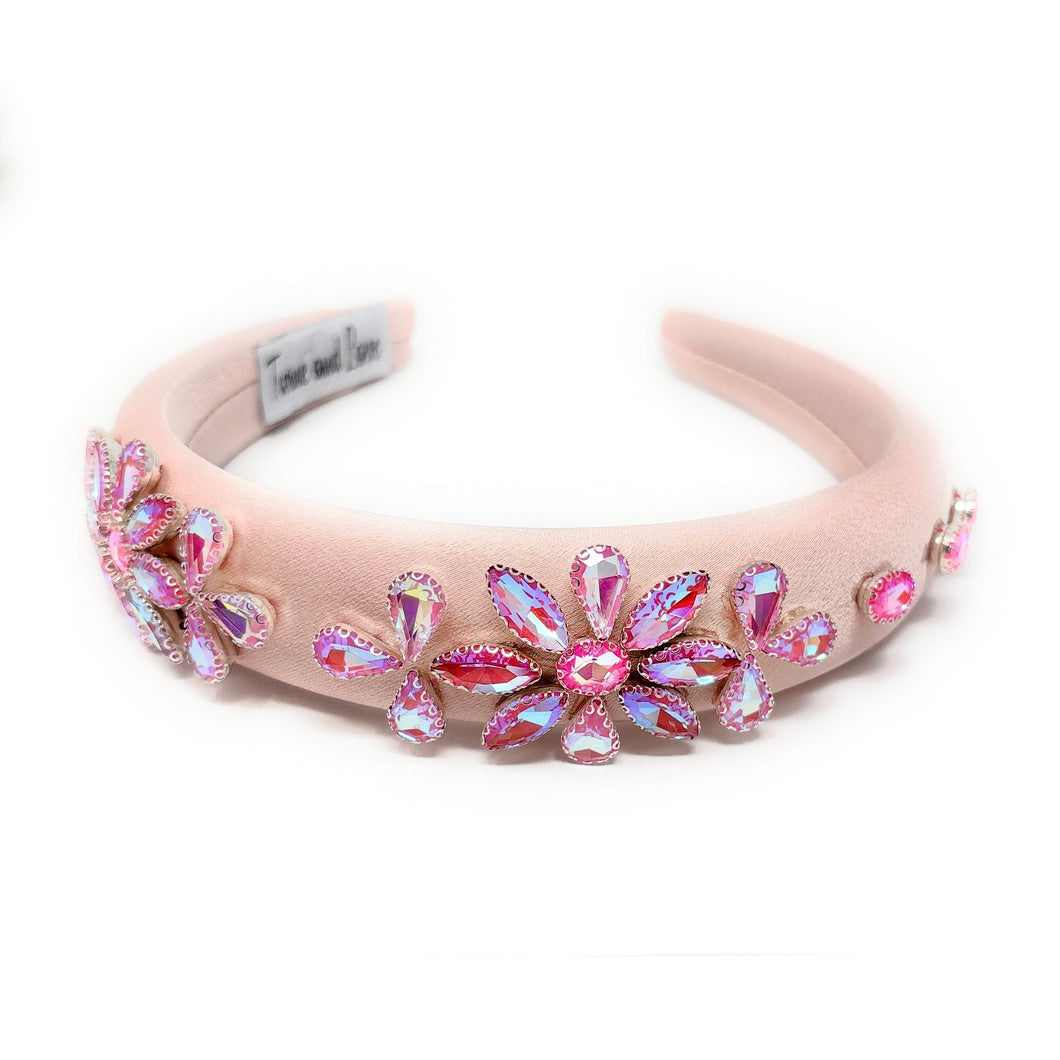 Pink headband with floral embellishments on a white background