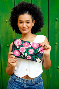 Woman holding a floral beaded clutch against a green background
