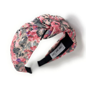 Floral headband with pink, purple, and dark green pattern on a white background. It features a central knot, creating a vibrant, stylish look.