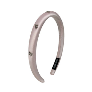Pink headband with small silver bows decorative charms on a white background