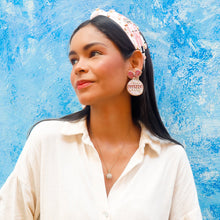 Load image into Gallery viewer, Woman wearing a white shirt, pink holiday earrings and headband against a blue textured wall