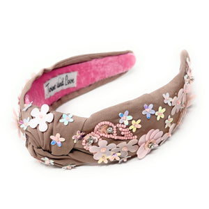 light Brown headband with pink interior, adorned with colorful floral applique and beading. The vibe is playful and feminine, showcasing detailed craftsmanship.