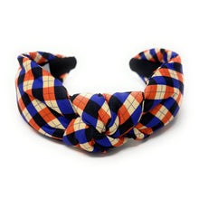 Load image into Gallery viewer, Colorful headband with a plaid pattern in red, blue, and beige hues against a white background. The fabric is knotted in the center, creating a playful and trendy accessory.