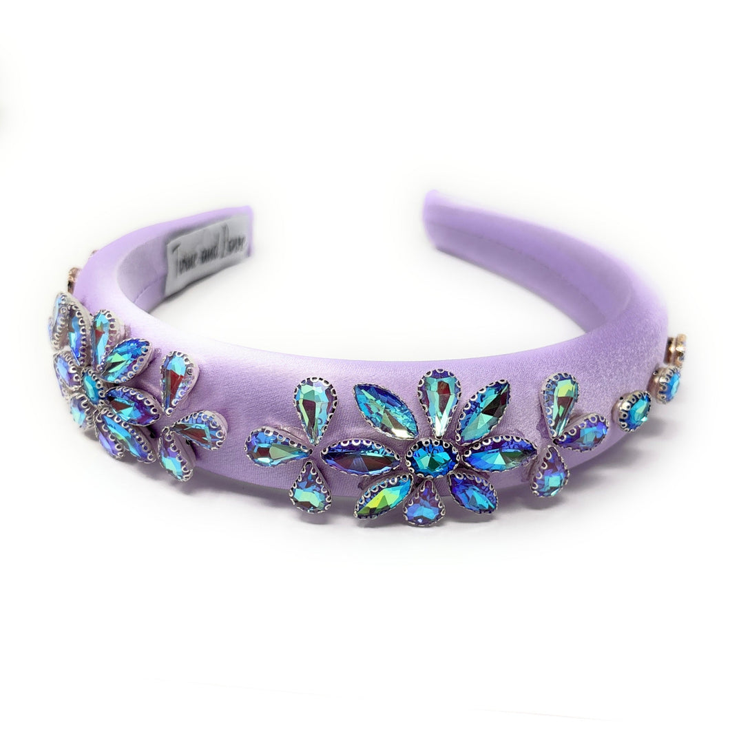 Purple headband adorned with iridescent crystal flowers. The crystals shimmer in blue and green tones, adding a touch of elegance and sparkle.