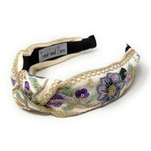 Load image into Gallery viewer, Elegant, floral-embroidered headband with gold detailing and a label inside. Features purple and sage green flowers on a cream background.