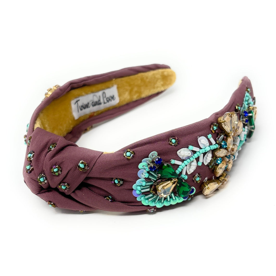 Ornate maroon headband with intricate blue and green beadwork, gold floral accents, and a soft yellow interior, evoking elegance and craftsmanship.