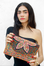 Load image into Gallery viewer, Handmade floral beaded clutch purse with bold pink petals and rainbow-inspired geometric accents, styled with an elegant black dress.
