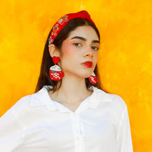 Load image into Gallery viewer, Woman wearing a white shirt, red headband, and blue jeans against a yellow background