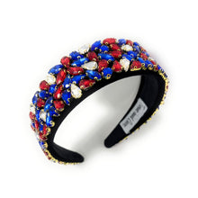 Load image into Gallery viewer, A wide, black headband adorned with vibrant red, blue, and clear gemstones arranged in clusters. The design conveys elegance and boldness.
