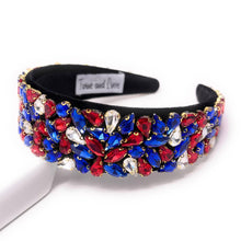 Load image into Gallery viewer, A wide, black headband adorned with vibrant red, blue, and clear gemstones arranged in clusters. The design conveys elegance and boldness.