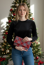 Load image into Gallery viewer, Woman holding a red and blue patterned heart-shaped object in front of a decorated Christmas tree.
