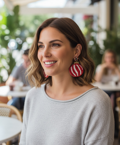 Woman wearing red and white striped earrings in an outdoor setting