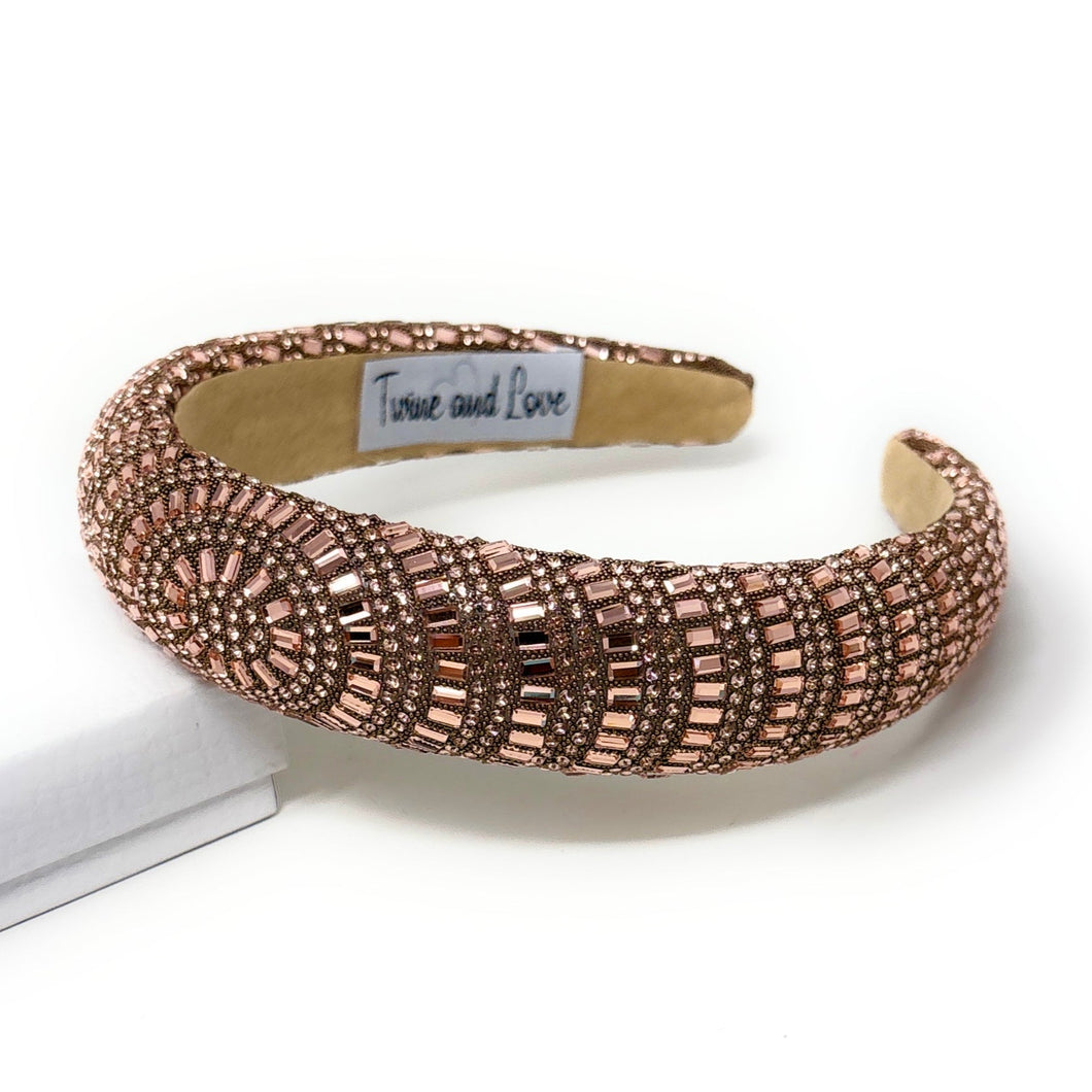 Elegant rose-gold headband adorned with intricate geometric beadwork on a neutral background. The label reads 