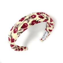 Load image into Gallery viewer, A cream-colored fabric headband with a pattern of red roses and green leaves on a white background. The headband is slightly arched, creating a soft, delicate look.