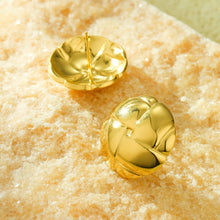 Load image into Gallery viewer, A pair of shiny gold-shaped stud earrings displayed on a textured beige stone surface.