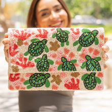 Load image into Gallery viewer, Beaded clutch with sea turtle design held by woman outdoors