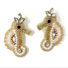 Load image into Gallery viewer, Elegant model showcasing a neutral tan headband and beaded seahorse earrings, paired with a chic black asymmetrical top.