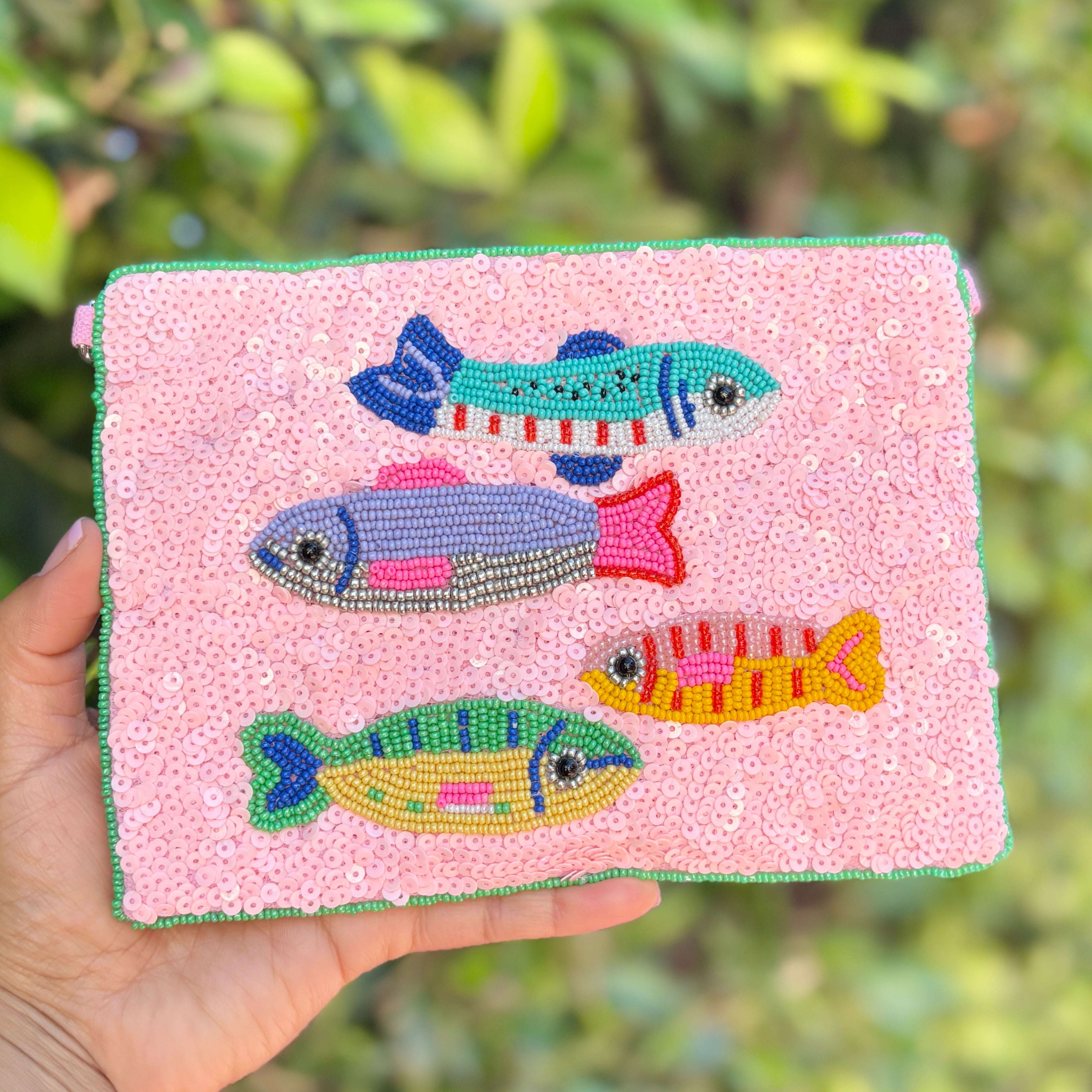 Fun nautical-inspired beaded pouch with multicolor fish designs on a sparkling pastel pink sequin background.