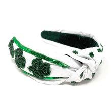 Load image into Gallery viewer, White headband with a knot, adorned with green sequined clovers and embroidery. The design conveys a festive, St. Patrick's Day theme.