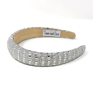 Elegant silver headband adorned with sparkling, intricate patterns and rhinestones, reflecting light. 