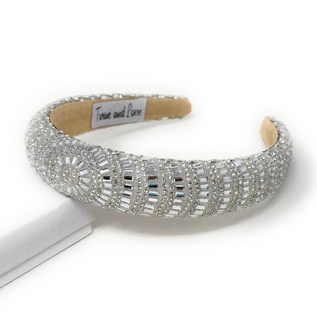 Elegant silver headband adorned with sparkling, intricate patterns and rhinestones, reflecting light. 
