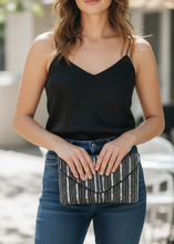 Load image into Gallery viewer, Woman holding a striped clutch purse outdoors
