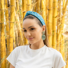 Load image into Gallery viewer, Close-up of a woman in a white shirt with a blue headband and statement earrings.