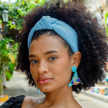Load image into Gallery viewer, Close-up portrait featuring a sky-blue twist headband paired with handcrafted bird-shaped earrings in turquoise, purple, and gold beadwork.