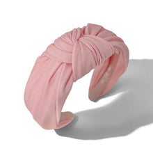 Load image into Gallery viewer, A soft pink twisted fabric headband with a knotted top detail, displayed on a clean white background with a soft shadow.