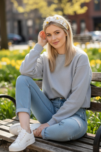 Load image into Gallery viewer, Woman sitting on a bench outdoors with a blurred background