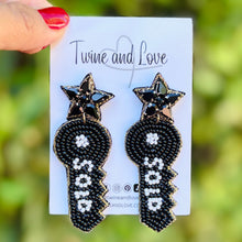 Load image into Gallery viewer, Black star earrings with geometric key design, adorned with white beaded accents. The glossy texture and intricate pattern create a bold, stylish look.